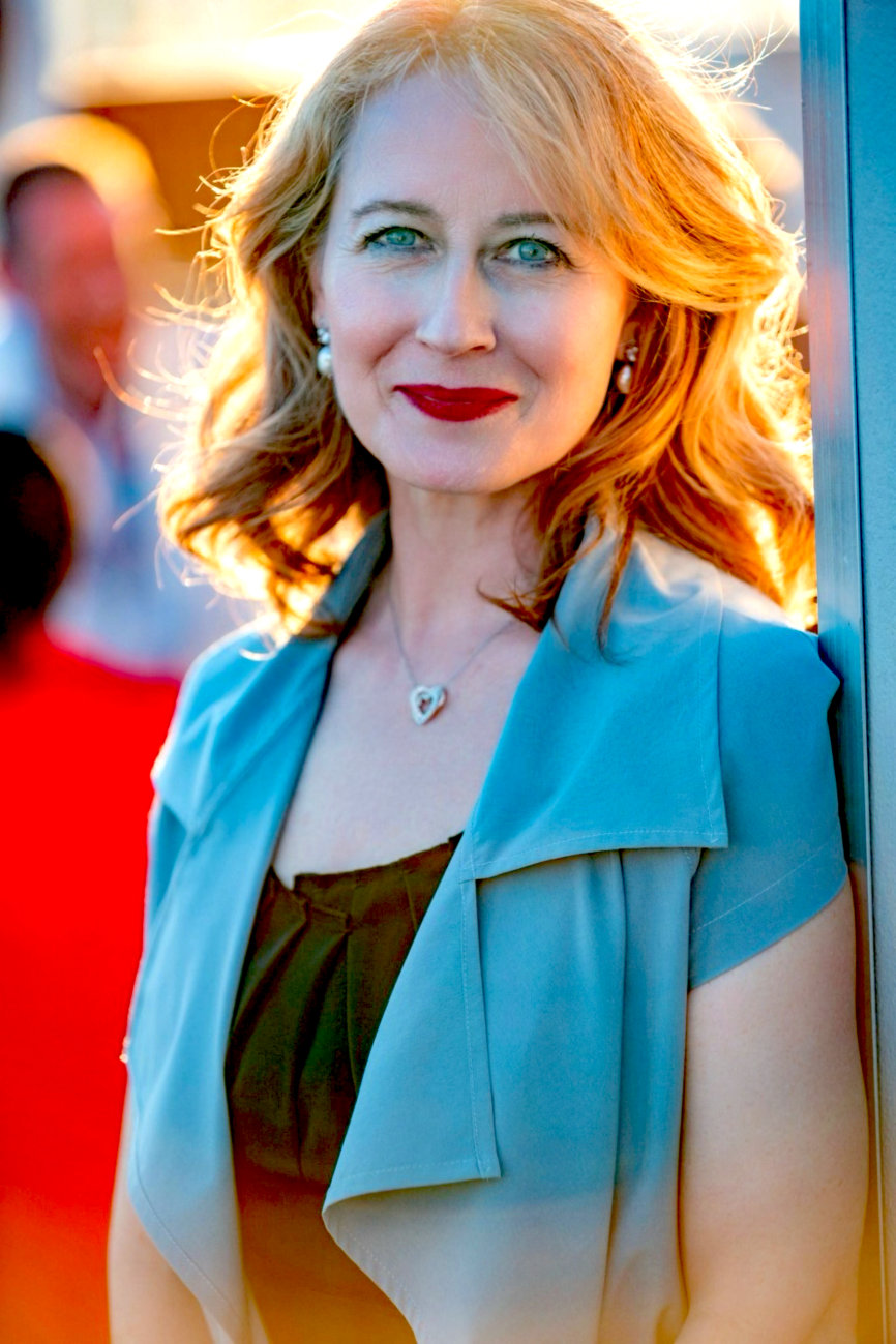 Image of ICDA President Lana Veenker wearing blue and black, backlit by a setting sun in Cannes.